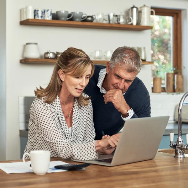 middle aged couple searching for new home on laptop